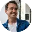 Man smiling in a casual denim jacket searches Atlas vs Ahrefs to compare backlink analyzer tools.