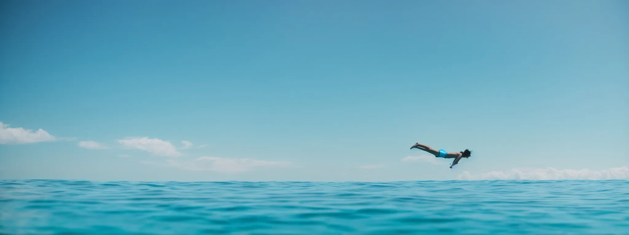a person diving from a springboard into a clear blue ocean symbolizing a deep dive into the digital world of seo and keywords.