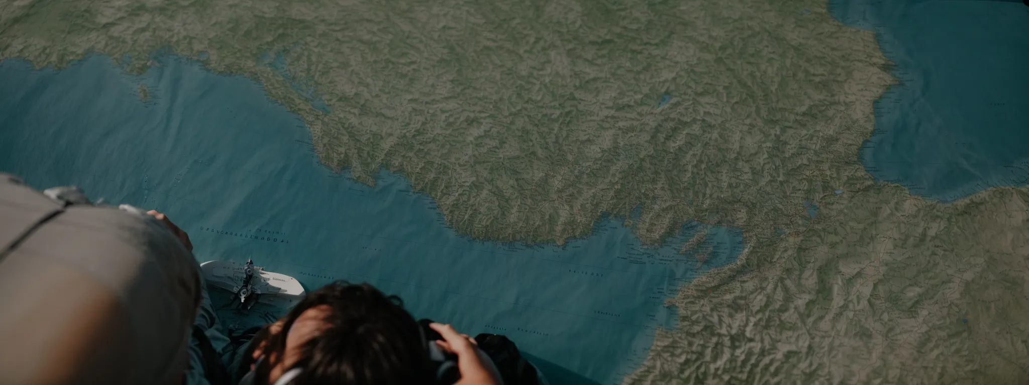 a person navigating a boat with a compass and map under the clear sky.