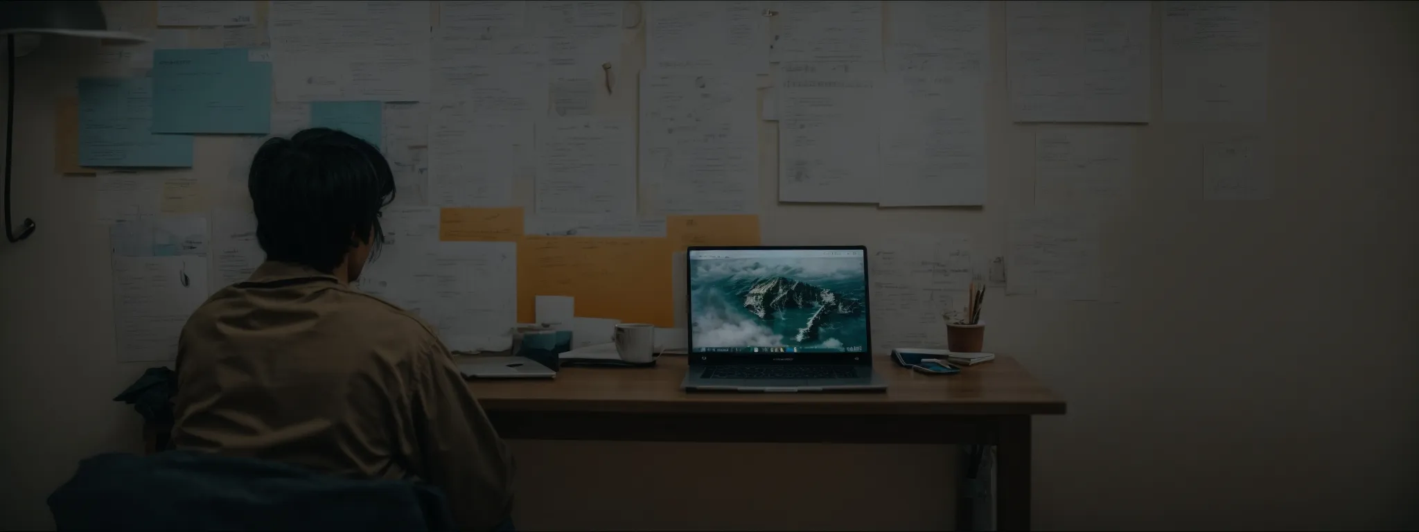 a person sitting with a laptop in front of a sprawling idea board, actively researching.
