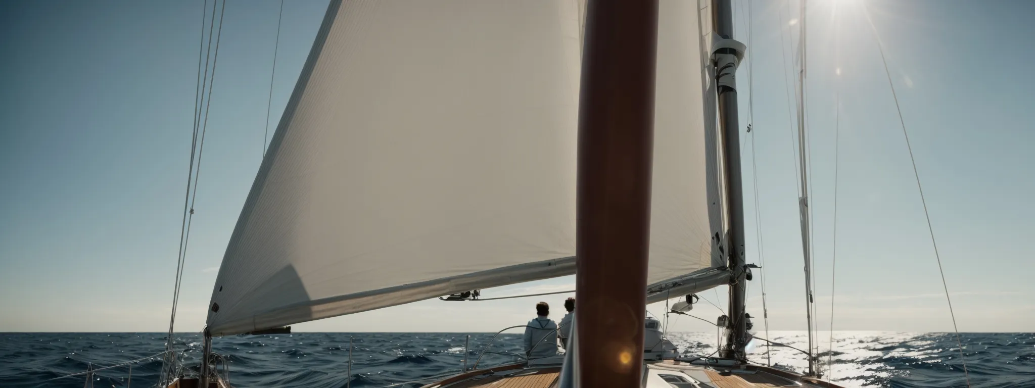 a person stands at the helm of a sailboat, navigating through a vast, open sea under a clear sky.