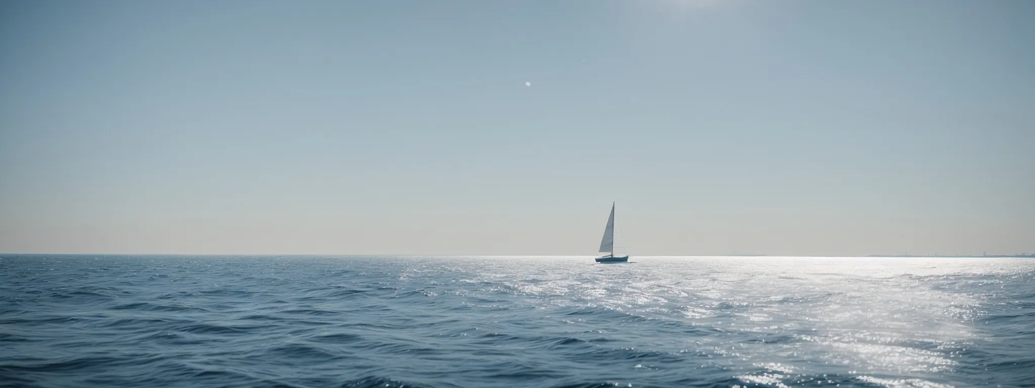 a sailboat gliding on vast open waters under a clear sky, emblematic of exploration.