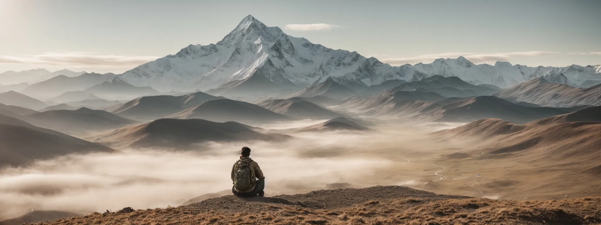 a person sits before a large, open landscape, pointing towards a distant mountain peak with a clear path ahead, symbolizing strategic direction in seo with searchatlas.